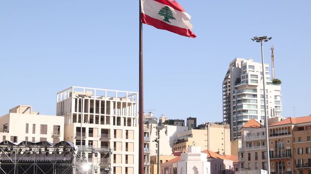 The national flag of Lebanon waving against the Beirut city background. Symbol of Lebanese identity, patriotism, and resilience located near the port area and urban skyline