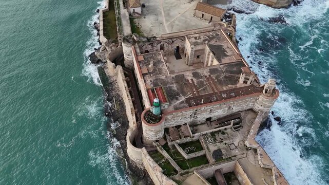 Top-down aerial shot of Castello Maniace on the tip of Ortigia Island, Syracuse. Dramatic view of the ancient fortress architecture surrounded by the deep blue Mediterranean sea