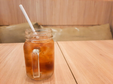 Mason jar of refreshing iced tea on wood background