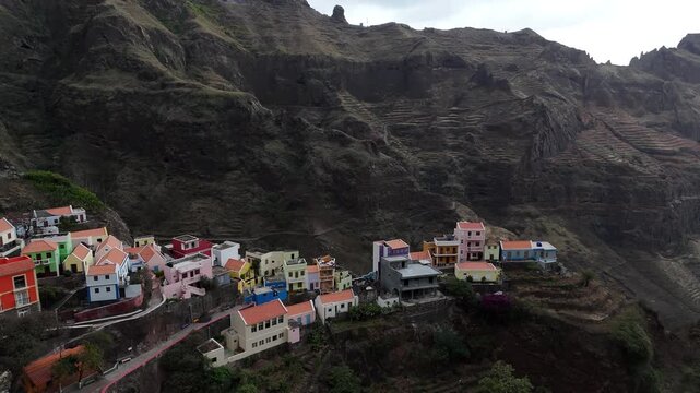 Dramatic aerial view of Fontainhas village nestled on a narrow mountain ridge in Santo Antao, Cape Verde. Drone footage of colorful houses overlooking a deep abyss in the volcanic peaks