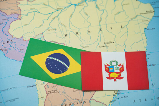Close up of Brazil and Peru flags on map of South America.