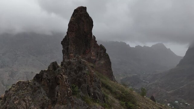 Dramatic aerial shot of a sharp basalt rock pinnacle rising from the misty mountains of Santo Antao, Cabo Verde. Unique geological formation in a rugged volcanic highland environment
