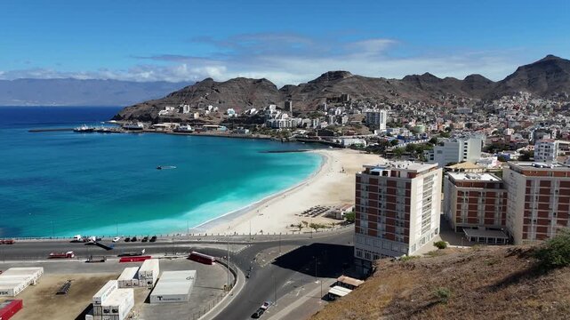 Aerial drone panoramic view of the bay of Mindelo, Sao Vicente. Coastal city architecture, Praia da Laginha beach, and the deep blue Atlantic ocean surrounded by volcanic peaks in Cape Verde