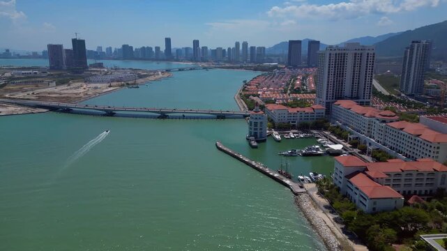 Kuala Juru river bridge connecting land reclamation and residential area with Georgetown city skyline and hills in background. Lovely aerial view rotation pan to left panorama drone