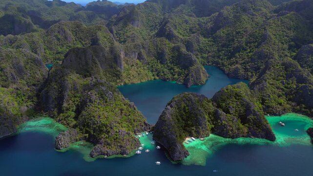 tropical Coron islands with limestone cliffs, lush green vegetation, and clear turquoise lagoons.ascending raise up panorama drone