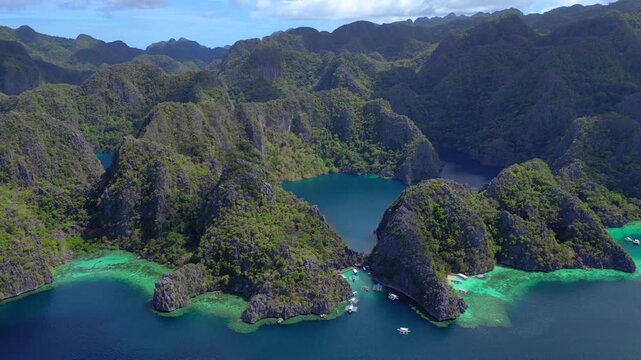 Azure waters of Barracuda Lake surrounded by lush green limestone karsts and anchored boats along the coastline. speed ramp hyper motion time lapse, Wonderful aerial view fly reverse panorama drone