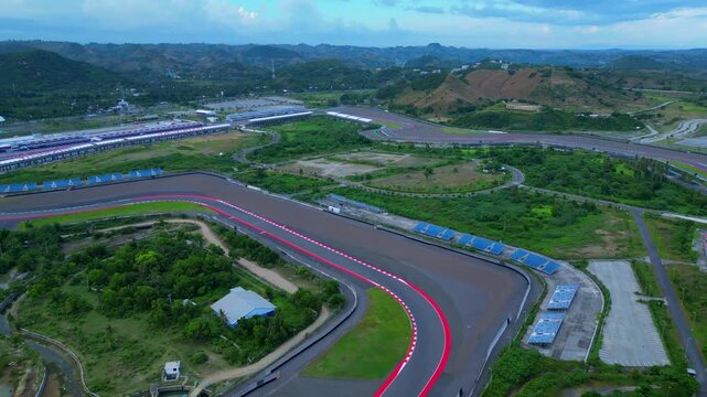 Mandalika International Street Circuit presenting its racing track lines and buildings against the beautiful blue ocean. speed ramp hyper motion time lapse Wonderful aerial view fly reverse panorama