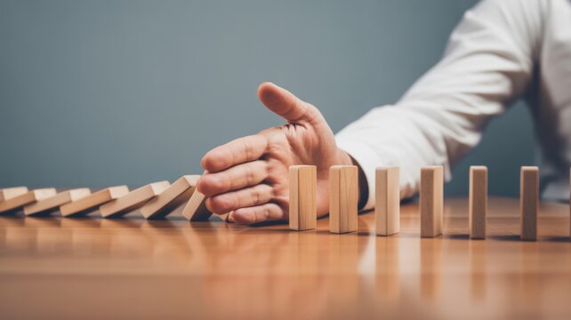 Hand stopping falling dominoes mid action symbolizing risk management crisis prevention and strategic decision making in business