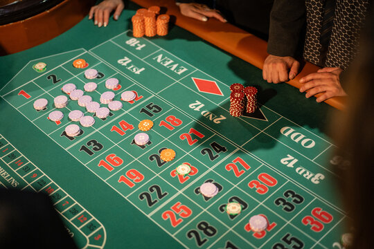 Players placing betting chips on a roulette table in a casino environment. Concept of gambling, risk, luck and chance.