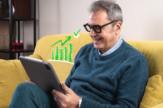Older man happily reviews financial growth data on digital tablet with positive performance graph.