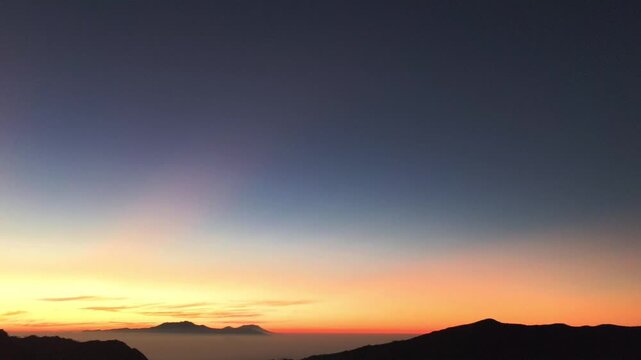 Beautiful sunset sky over mountain range with soft gradient colors and calm horizon, cinematic landscape footage, tranquil evening scene perfect for travel, nature and inspirational backgrounds