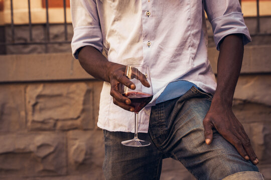Man holding glass of red wine outdoors during summer evening