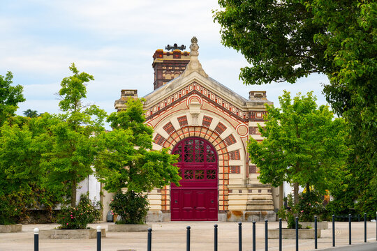 Ornate facade of the historic Arsenal building in Dreux, featuring decorative polychrome brickwork and a grand red arched gateway, France
