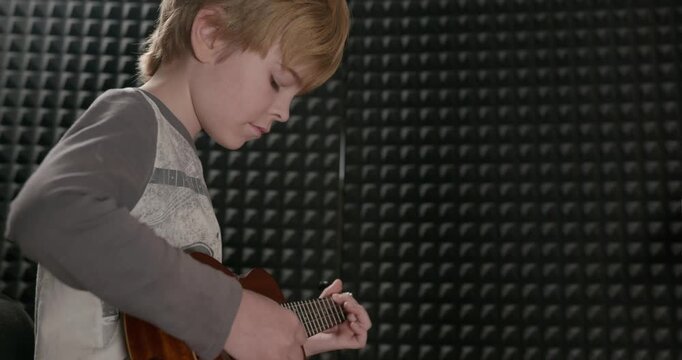 Boy Play Music on Ukulele Instrument in Home Studio. 4K 10-bit