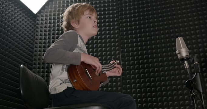 Boy Play Music on Ukulele Instrument in Home Studio. 4K 10-bit