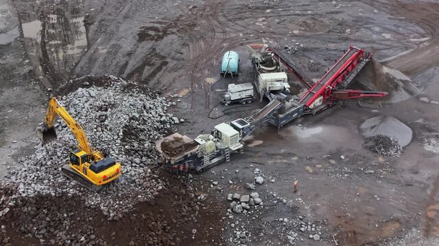 Aerial drone shot of a vibrating screen stone crusher actively working quarry near Halifax, Nova Scotia. Large machinery processes limestone and stones for cement and construction industry in Canada