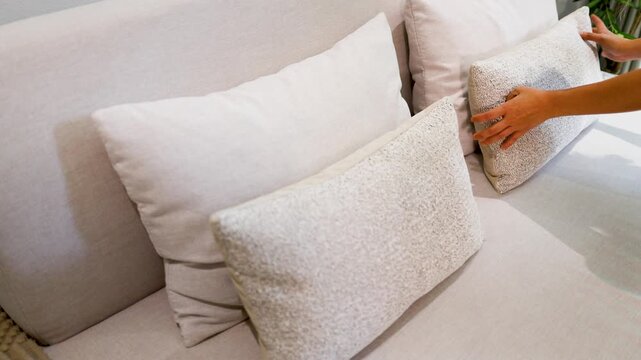 Asian Woman Hands Arranging Decorative Pillows on a Modern Living Room Sofa