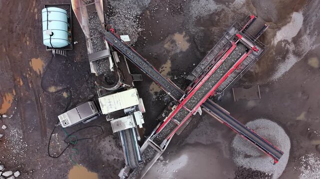 Top View drone aerial view of a mobile stone crusher with vibrating screen in operation at a quarry near Halifax, Nova Scotia. Processing rocks into aggregates for Canadian construction industry 4K.