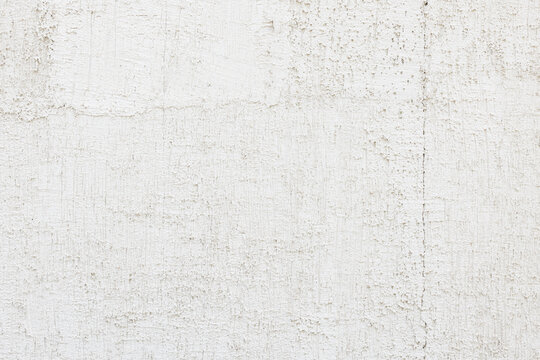 Textured white wall with cracks on building facade
