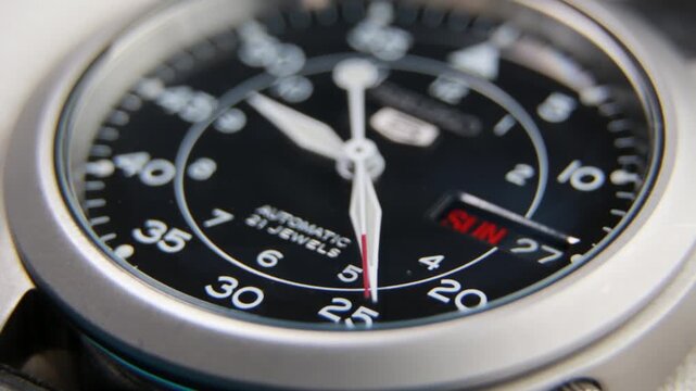 Macro close up of an automatic mechanical field watch with moving arms
