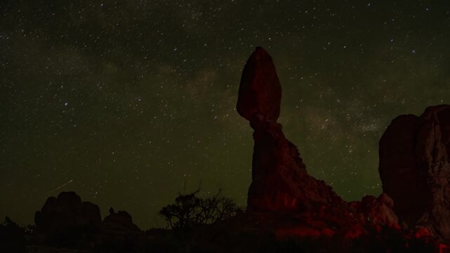 Milky Way timelapse over Balanced Rock in Arches National Park near Moab Utah United States with visible galactic core and dense star field in a certified dark sky desert environment, static nighttime