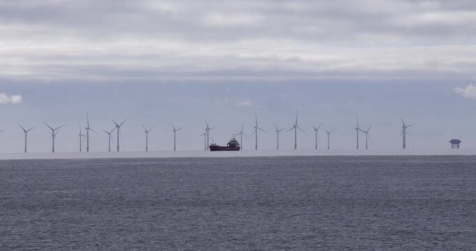Wide shot of a ship in front of wind turbines in the sea of Shoreham