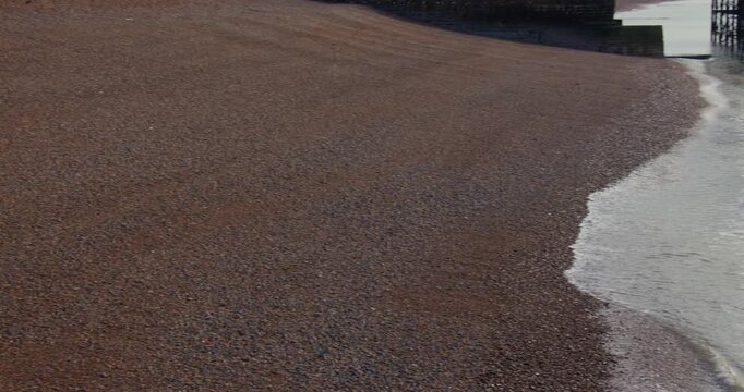 Panning Shot off waves breaking on a Pebble gravel beach at Brighton