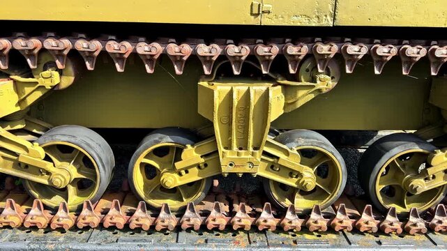 Sideways dolly shot revealing close-up details of rusty WWII tank tracks, grousers, road wheels and yellow suspension at Overlord Museum in Normandy, France