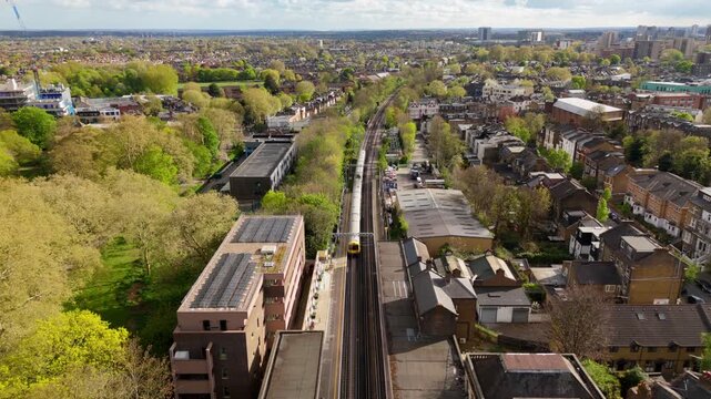 Aerial birds eye view train travelling into distance in suburban town