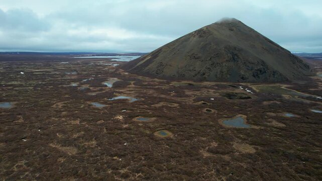 Vindbelgjarfjall: Drone footage flying over a desolate volcanic tundra in Iceland, revealing small geothermal pools and a prominent conical volcano