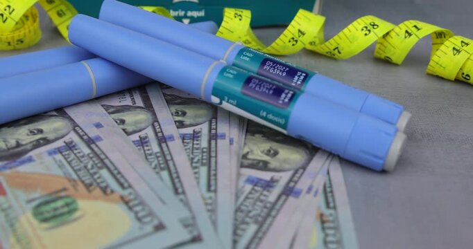 Moving view of semaglutide pens with yellow tape on cash for illustrating medical expenses and skin folds from extreme weight loss.