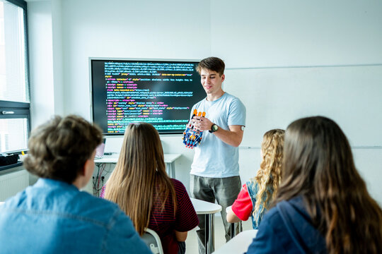 Teen boy presenting robotic project in front of classroom.