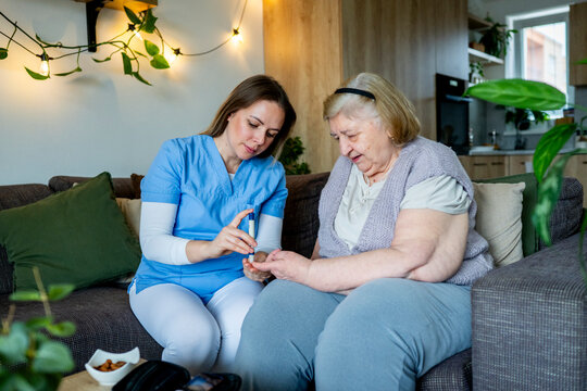 Diabetologist nurse testing blood sample on blood sugar meter.