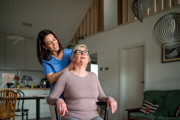 Fototapeta premium Physiotherapist helping senior woman with neck exercise, home therapy session.