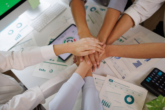 Business people stacking hands on corporate documents