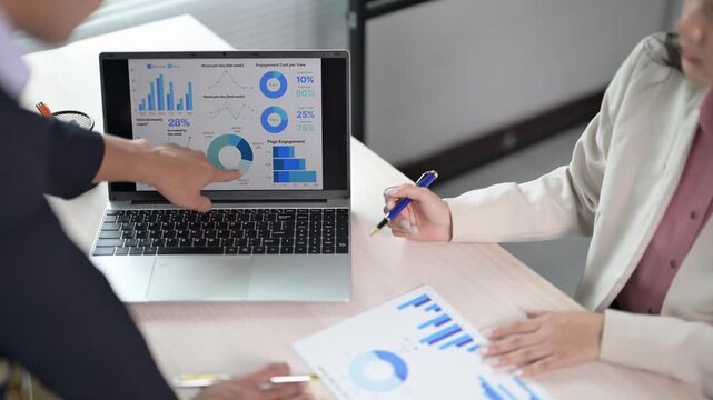 Business Meeting with Laptop and Chart Presentations on Table