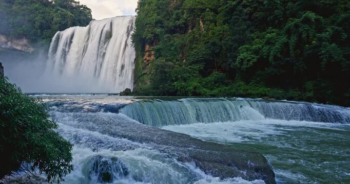 Powerful Huangguoshu waterfall cascading into a river with lush tropical vegetation in Anshun, Guizhou, China