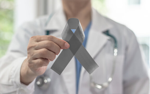Brain cancer awareness with grey ribbon on doctor's hand, symbolic bow gray color for Allergies, Alpha-1 Antitrypsin Deficiency, Aphasia, Asthma, Borderline Personality Disorder