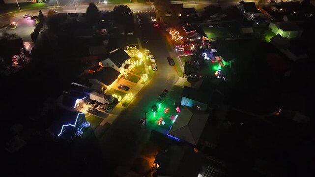 Cinematic aerial drone view of neighborhood houses decorated with festive Christmas lights at night Centralia, Washington
