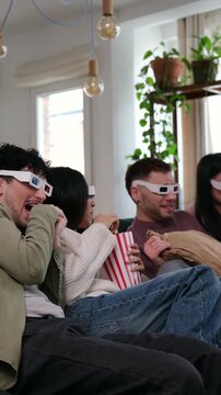 Group of diverse friends wearing 3d glasses watching a film and eating popcorn at home