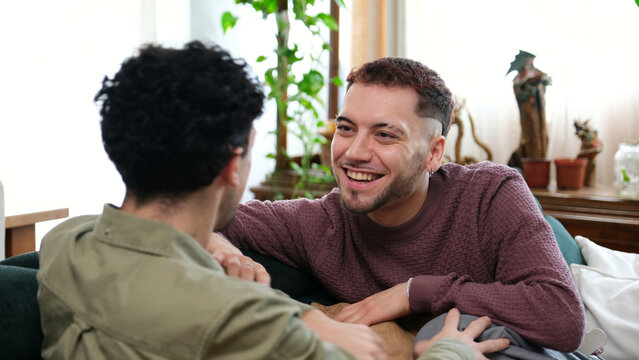 Young men bonding and smiling at each other in a relaxing domestic setting