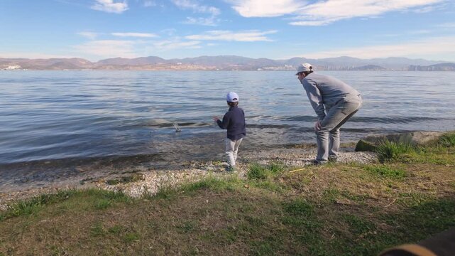 Father and son skipping stones by the lake