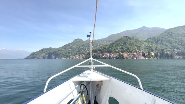 Front bow view of boat moving across Lake Como, dynamic forward motion on water with scenic mountains and travel journey concept in Italy