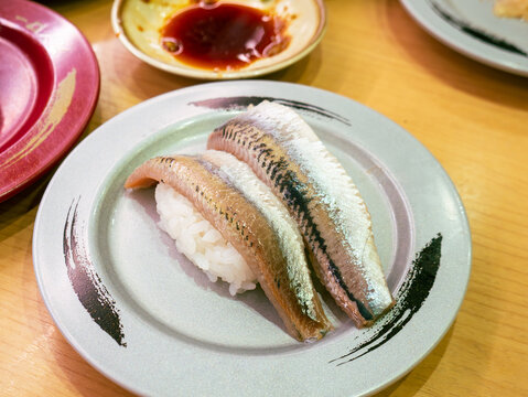 Fresh whole sardine or iwashi nigiri sushi two pieces on ceramic plate with shiny silver skin, Japanese restaurant