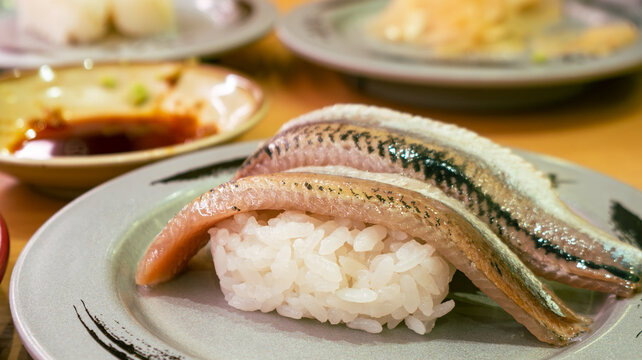 Fresh whole sardine or iwashi nigiri sushi two pieces on ceramic plate with shiny silver skin, Japanese restaurant