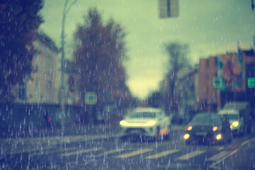 Fototapeta premium Rainy weather background on a city street, road with cars and drops of autumn rain in blur