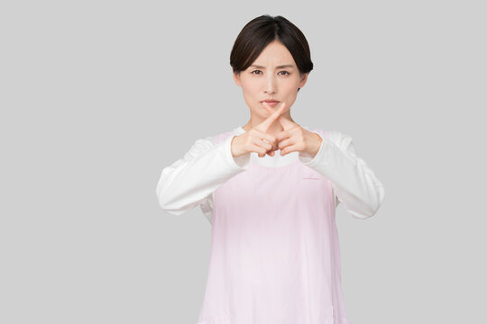 両手でバツ印を作るエプロン姿の女性（禁止・拒絶・NGイメージ）