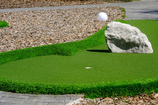 Mini golf course obstacle with white ball near hole