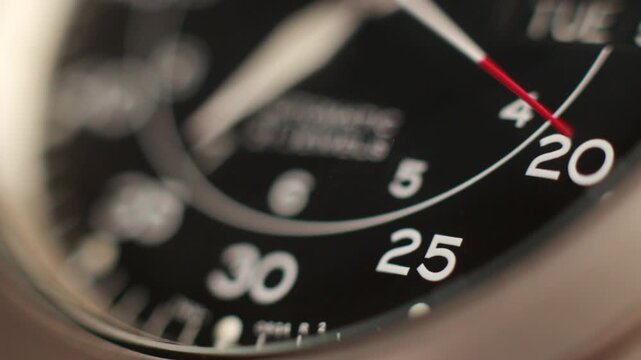 Macro close up of an automatic mechanical field watch with moving arms
