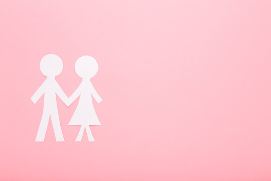 Woman and man white paper shapes on light pink table background. Pastel color. Love concept. Closeup. Empty place for text. Flat lay. Top down view.